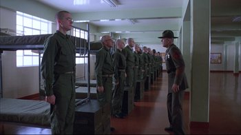 Movie still from “Full Metal Jacket” (1987), directed by Stanley Kubrick – A group of men standing in a line in a room; Wide shot, Low angle