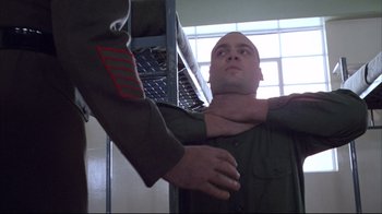 Movie still from “Full Metal Jacket” (1987), directed by Stanley Kubrick – A man in a green shirt is being held by another man in a green shirt; Close Up shot, Low angle