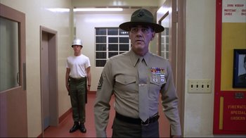 Movie still from “Full Metal Jacket” (1987), directed by Stanley Kubrick – A man in uniform standing next to another man in a hat; Medium shot, Low angle