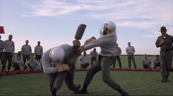 Movie still from “Full Metal Jacket” (1987), directed by Stanley Kubrick – A group of men playing baseball on a field; Wide shot, Over the shoulder angle