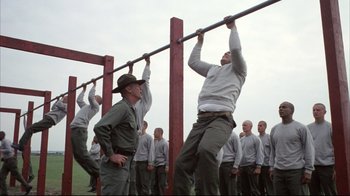 Movie still from “Full Metal Jacket” (1987), directed by Stanley Kubrick – A group of men doing pull - ups on a bar; Wide shot, Low angle