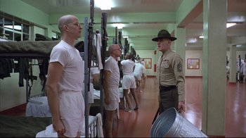 Movie still from “Full Metal Jacket” (1987), directed by Stanley Kubrick – A group of men standing next to each other in a room; Wide shot, Low angle