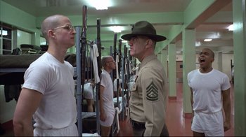Movie still from “Full Metal Jacket” (1987), directed by Stanley Kubrick – A man in a uniform talking to another man in a uniform; Medium shot, Low angle