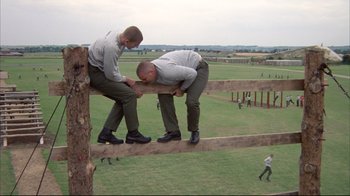 Movie still from “Full Metal Jacket” (1987), directed by Stanley Kubrick – A couple of men standing on top of a wooden structure; Wide shot, Low angle