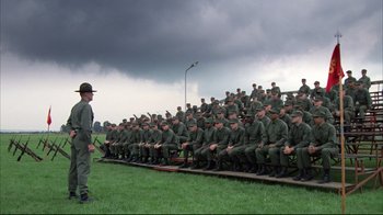 Movie still from “Full Metal Jacket” (1987), directed by Stanley Kubrick – A group of men sitting in front of a man in uniform; Wide shot, High angle