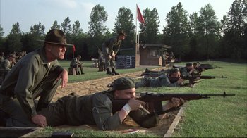 Movie still from “Full Metal Jacket” (1987), directed by Stanley Kubrick – A group of men in military fatigues are laying on the ground and aiming rifles; Wide shot, High angle