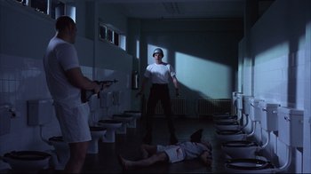Movie still from “Full Metal Jacket” (1987), directed by Stanley Kubrick – A man standing in a room next to a dead man laying on the ground; Wide shot, Low angle