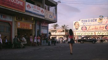 Movie still from “Full Metal Jacket” (1987), directed by Stanley Kubrick – A woman walking down a street near a building; Extreme Wide shot, Over the shoulder angle