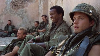 Movie still from “Full Metal Jacket” (1987), directed by Stanley Kubrick – A group of men sitting next to each other on a wall; Medium shot, Low angle