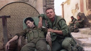 Movie still from “Full Metal Jacket” (1987), directed by Stanley Kubrick – A man and a soldier sitting next to each other on a chair; Medium shot, High angle