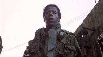 Movie still from “Full Metal Jacket” (1987), directed by Stanley Kubrick – A man in a green jacket and a gas mask; Close Up shot, Low angle