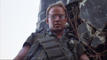Movie still from “Full Metal Jacket” (1987), directed by Stanley Kubrick – A man wearing glasses and a vest and holding a gun; Close Up shot, Low angle