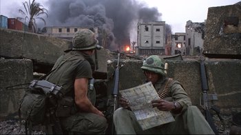 Movie still from “Full Metal Jacket” (1987), directed by Stanley Kubrick – Two men sitting on the side of a building looking at a map; Medium shot, High angle