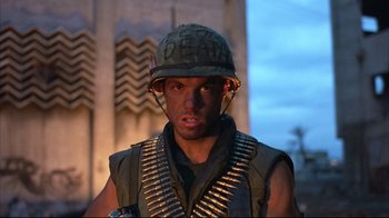 Movie still from “Full Metal Jacket” (1987), directed by Stanley Kubrick – A man wearing a helmet and a vest with bullet casings on his head; Close Up shot, Low angle