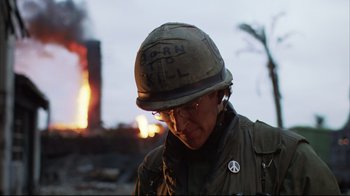 Movie still from “Full Metal Jacket” (1987), directed by Stanley Kubrick – A man wearing a helmet with a peace sign on it; Close Up shot, Low angle