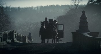 Movie still from “The Wolfman” (2010), directed by Joe Johnston – A horse drawn carriage traveling down a road in the fog; Wide shot, Low angle