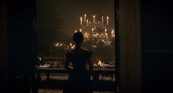 Movie still from “The Wolfman” (2010), directed by Joe Johnston – A woman standing in front of a large chandelier; Wide shot, Over the shoulder angle