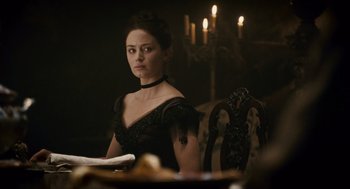 Movie still from “The Wolfman” (2010), directed by Joe Johnston – A woman sitting at a table in front of candles; Medium shot, Over the shoulder angle