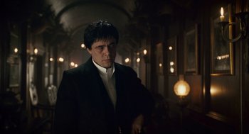 Movie still from “The Wolfman” (2010), directed by Joe Johnston – A man wearing a suit and tie standing in a room; Medium shot, Low angle