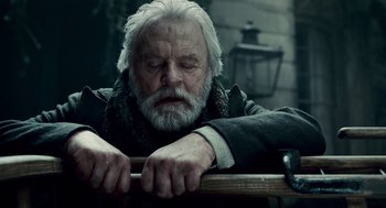 Movie still from “The Wolfman” (2010), directed by Joe Johnston – An old man with a beard is leaning on a railing; Close Up shot, Over the shoulder angle