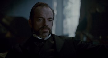 Movie still from “The Wolfman” (2010), directed by Joe Johnston – A man with a beard and mustache wearing a suit and tie; Close Up shot, Over the shoulder angle