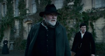 Movie still from “The Wolfman” (2010), directed by Joe Johnston – An older man wearing a black hat and a black coat; Medium shot, Low angle