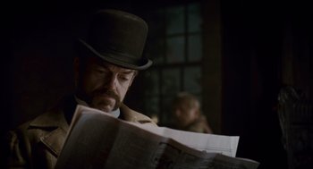 Movie still from “The Wolfman” (2010), directed by Joe Johnston – A man wearing a top hat reading a newspaper; Close Up shot, Over the shoulder angle