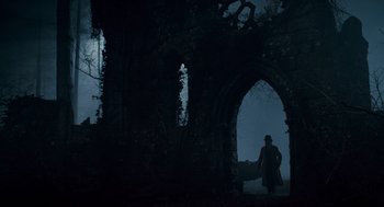 Movie still from “The Wolfman” (2010), directed by Joe Johnston – A man in a top hat walks through an archway in the dark; Wide shot, Low angle