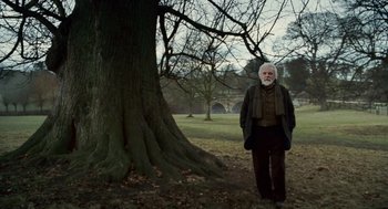 Movie still from “The Wolfman” (2010), directed by Joe Johnston – An older man standing in front of a large tree; Wide shot, Low angle
