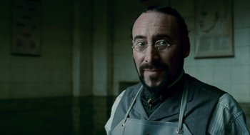 Movie still from “The Wolfman” (2010), directed by Joe Johnston – A man with a beard and glasses in a room; Close Up shot, Low angle