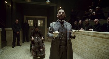 Movie still from “The Wolfman” (2010), directed by Joe Johnston – A man with a cane standing next to another man in a wheelchair; Medium shot, Low angle