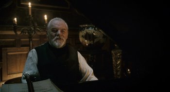 Movie still from “The Wolfman” (2010), directed by Joe Johnston – An older man sitting at a piano in a dark room; Medium shot, Low angle