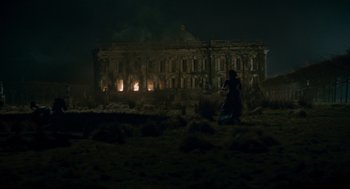 Movie still from “The Wolfman” (2010), directed by Joe Johnston – A woman in a long blue dress standing in front of an old building; Extreme Wide shot, Low angle