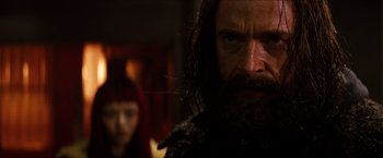 A man with long hair and a beard stares at the camera
