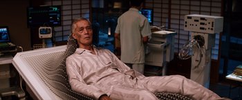 Movie still from “The Wolverine” (2013), directed by James Mangold – An older man is sitting on a chair in a room; Medium shot, High angle