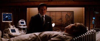 Movie still from “The Wolverine” (2013), directed by James Mangold – A man standing next to an older man in front of a bed; Medium shot, Low angle