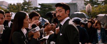 Movie still from “The Wolverine” (2013), directed by James Mangold – A man in a black suit is being interviewed by reporters; Close Up shot, Low angle