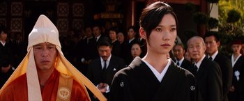 A woman in a black kimono is standing in front of a group of people