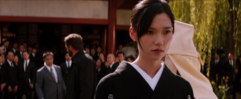 Movie still from “The Wolverine” (2013), directed by James Mangold – A young woman in a black kimono stands in front of a group of people; Close Up shot, Over the shoulder angle