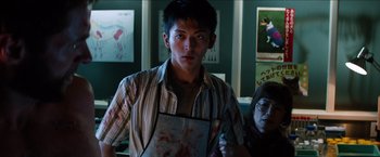 Movie still from “The Wolverine” (2013), directed by James Mangold – A young man holding a piece of paper in front of a young woman; Medium shot, Low angle