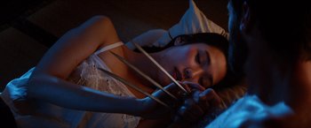 Movie still from “The Wolverine” (2013), directed by James Mangold – A woman laying in a bed holding a pair of wolverine claws; Close Up shot, High angle