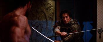 Movie still from “The Wolverine” (2013), directed by James Mangold – A man holding two swords in front of a wall; Medium shot, Over the shoulder angle