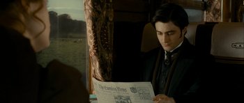 Movie still from “The Woman in Black” (2012), directed by James Watkins – A man sitting on top of a train looking at a newspaper; Medium shot, Over the shoulder angle