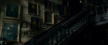 Movie still from “The Woman in Black” (2012), directed by James Watkins – A staircase with a bunch of paintings on the wall; Wide shot, Low angle