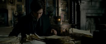Movie still from “The Woman in Black” (2012), directed by James Watkins – A man sitting at a table with a lot of papers; Medium shot, High angle