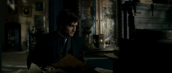 Movie still from “The Woman in Black” (2012), directed by James Watkins – A man sitting at a table in a dark room; Medium shot, High angle