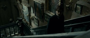 Movie still from “The Woman in Black” (2012), directed by James Watkins – A man standing on the stairs in a dark room; Medium shot, Low angle