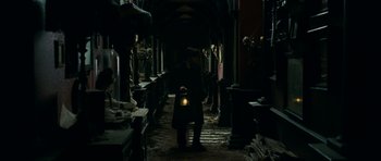 Movie still from “The Woman in Black” (2012), directed by James Watkins – A man holding a lantern in a dark room; Wide shot, High angle