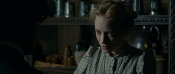 Movie still from “The Woman in Black” (2012), directed by James Watkins – A woman in a plaid shirt in front of a shelf; Close Up shot, Over the shoulder angle