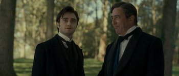 Movie still from “The Woman in Black” (2012), directed by James Watkins – A man and a man standing next to each other; Medium shot, Over the shoulder angle